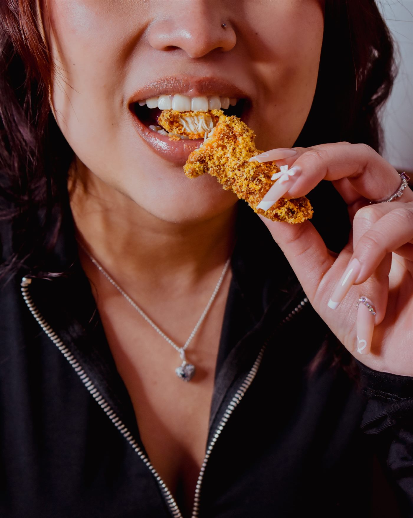 Chica mordiendo un finger de pollo crujiente